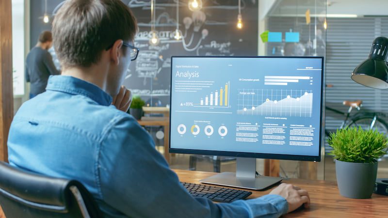 Man looking at charts and data on a computer in a modern office