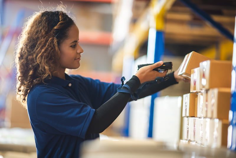 woman counting inventory of boxes in a warehouse