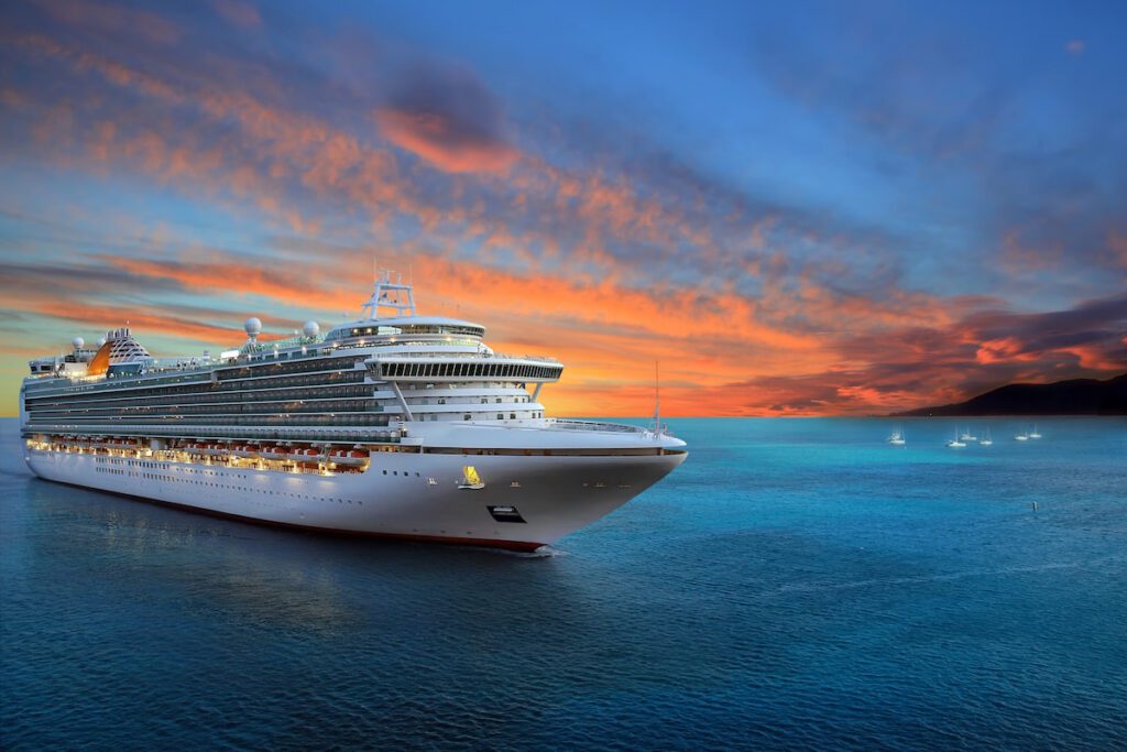 A cruise ship sailing on the ocean as the sun sets
