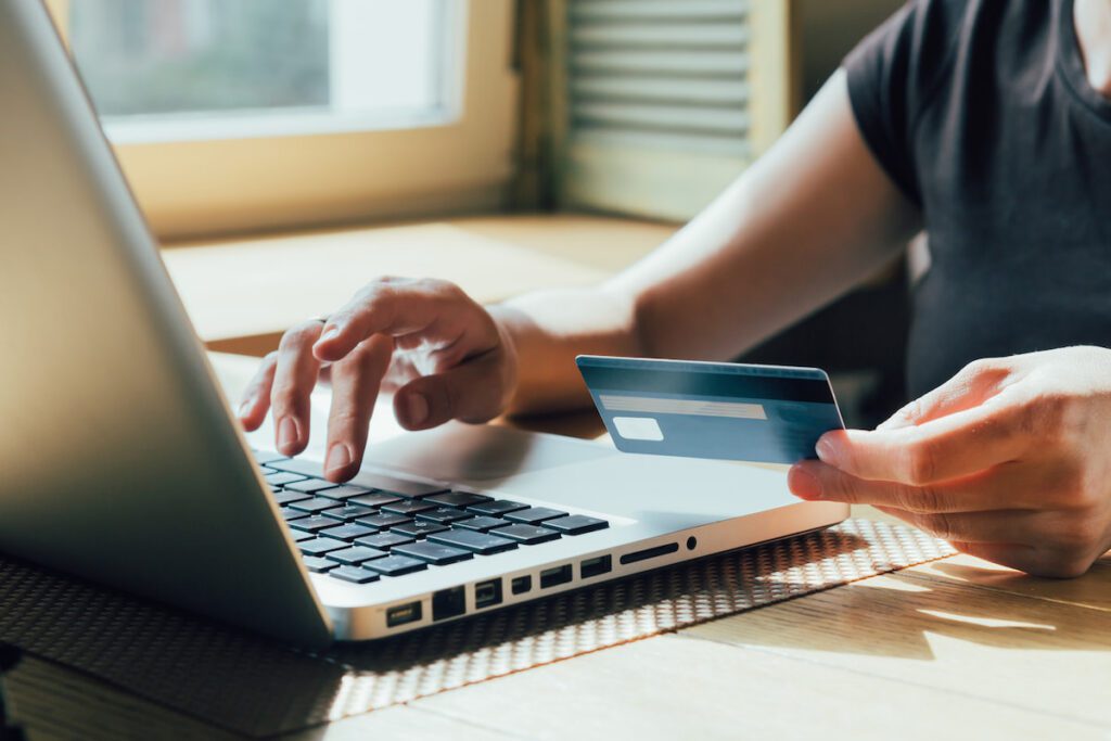 Woman sitting at her computer making a purchase online with a credit card